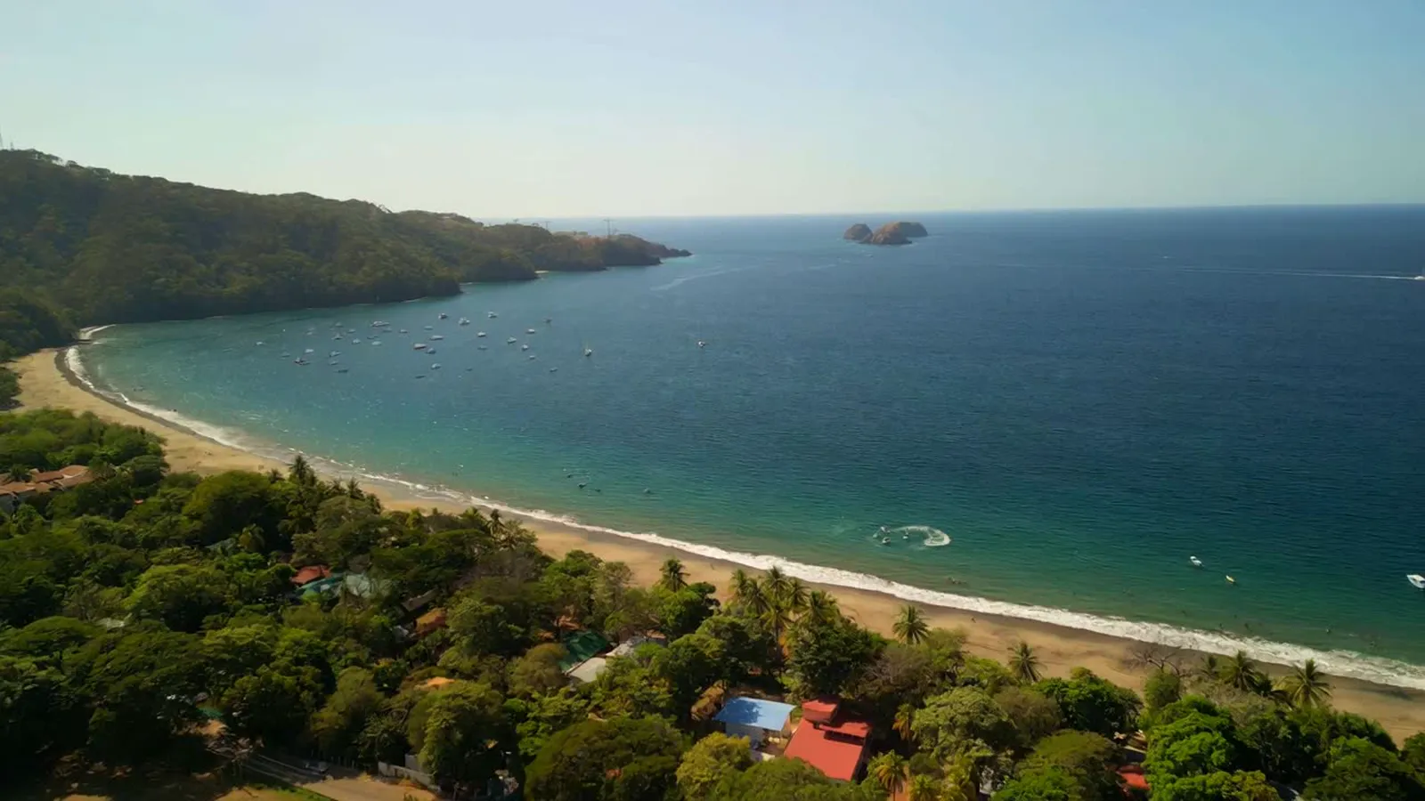 Aerial view of Playa Hermosa, with the beach, the bay and rooftops in the trees